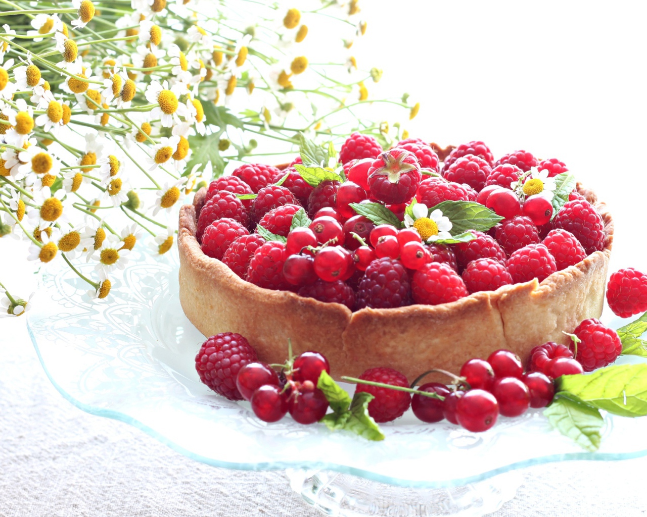 Пирог с ягодами малины и смородины на столе с ромашками