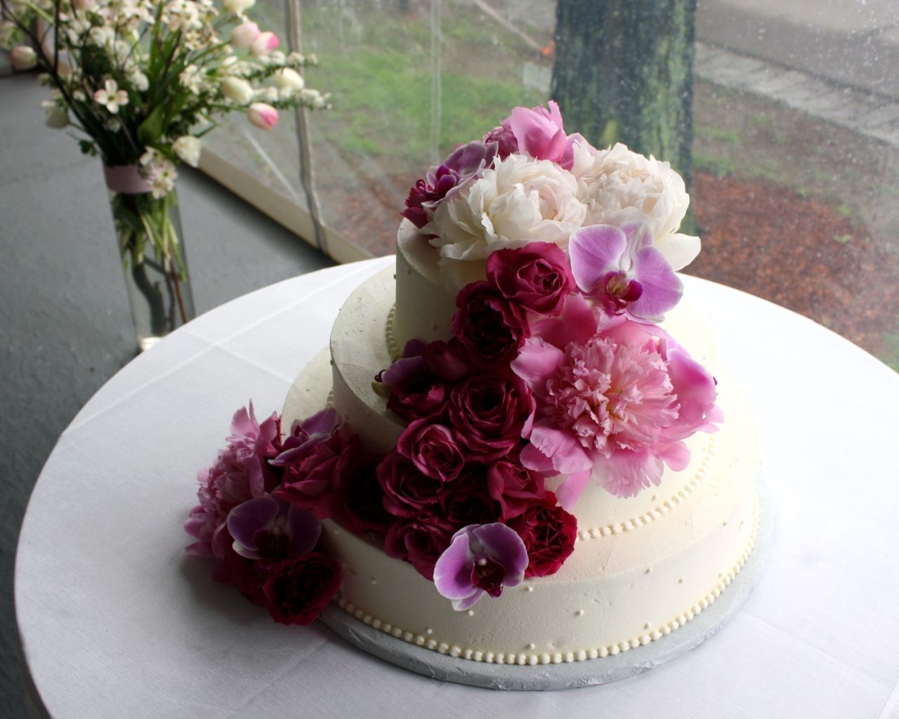 Большой свадебный торт украшен живыми цветами