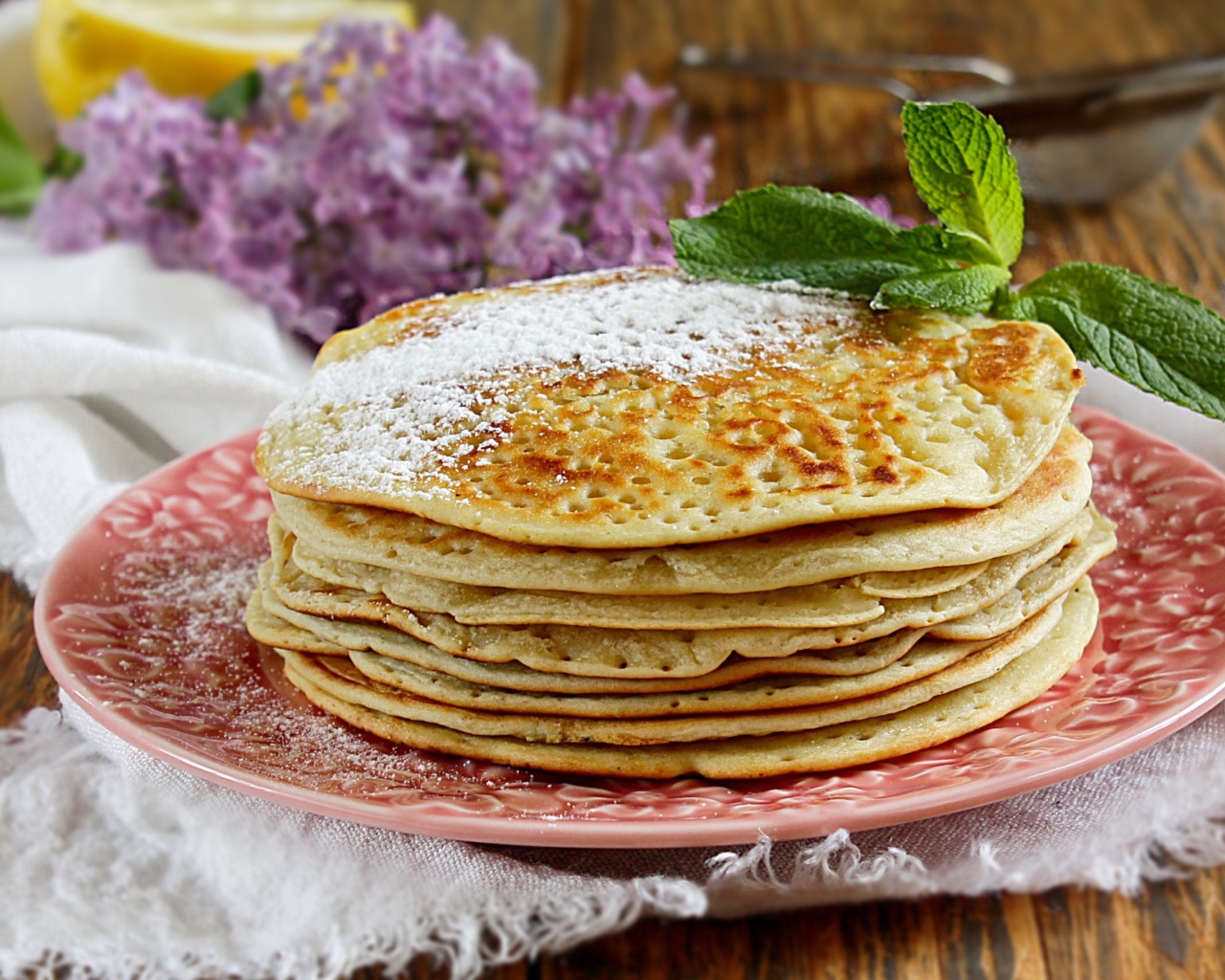 Тонкие блинчики на тарелке с сахарной пудрой и веточкой мяты