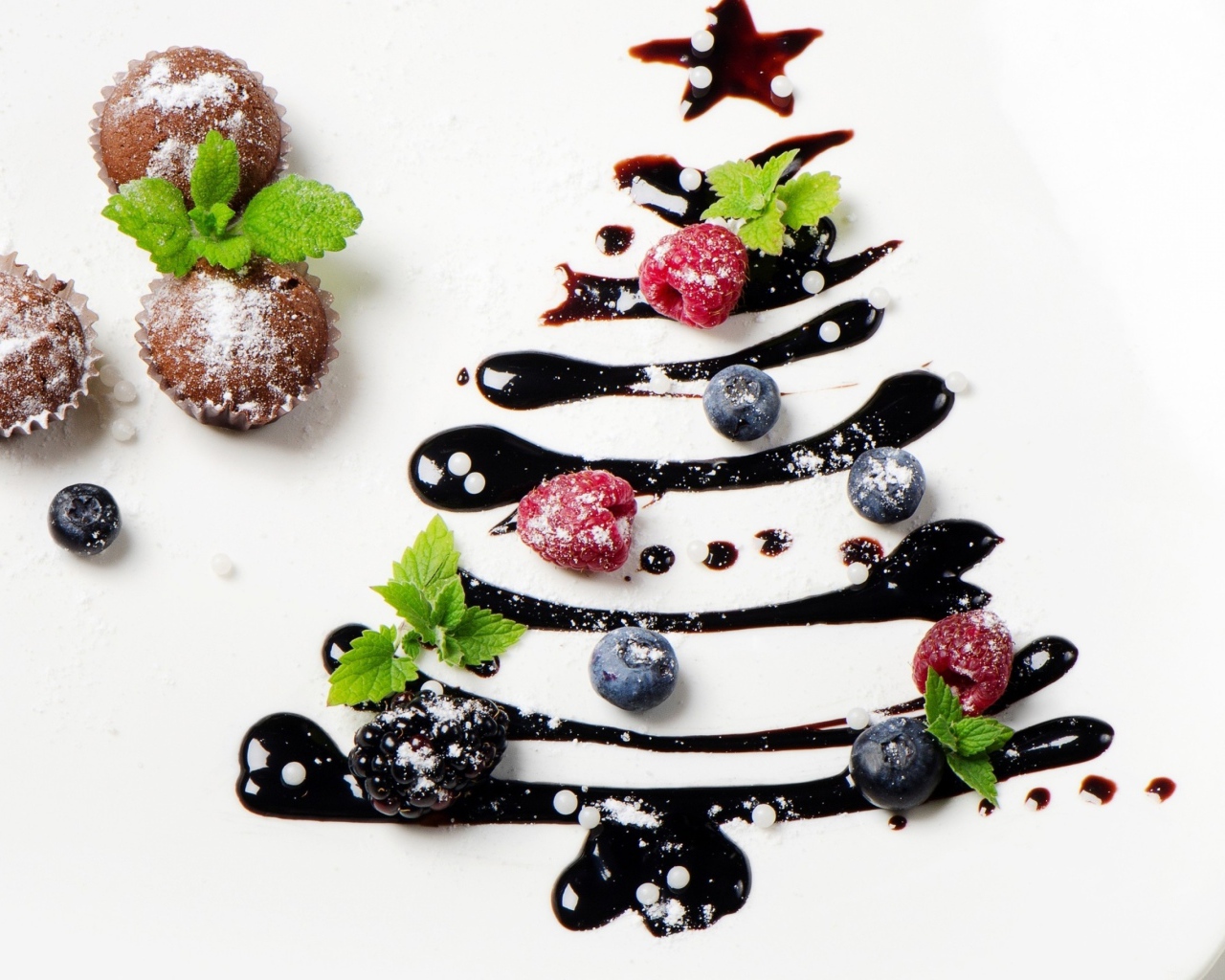 Три кекса и нарисованная шоколадом елка на белой тарелке