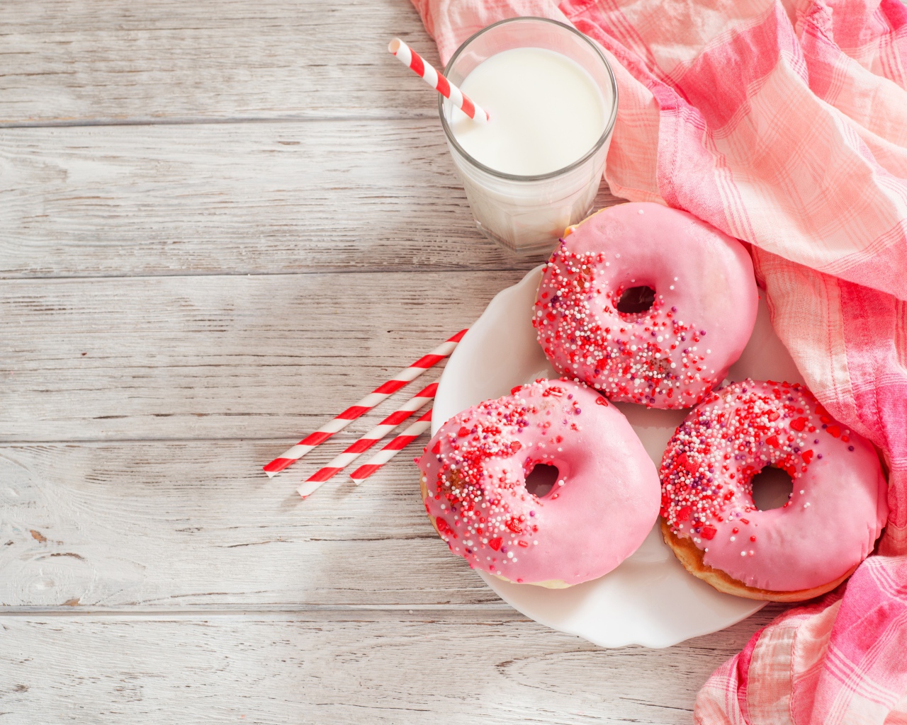 Три аппетитных пончика с розовой сахарной слазурью и стаканом молока