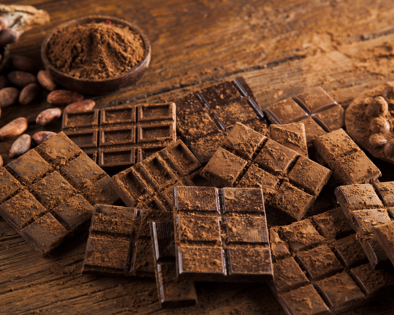 Плитки черного шоколада на столе с какао бобами