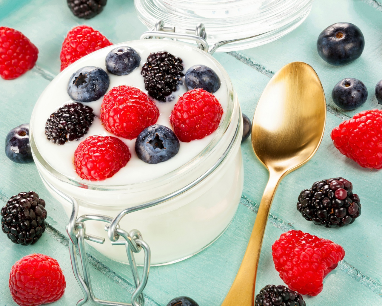 Йогурт со свежими ягодами малины, черники и ежевики в стеклянной банке на завтрак