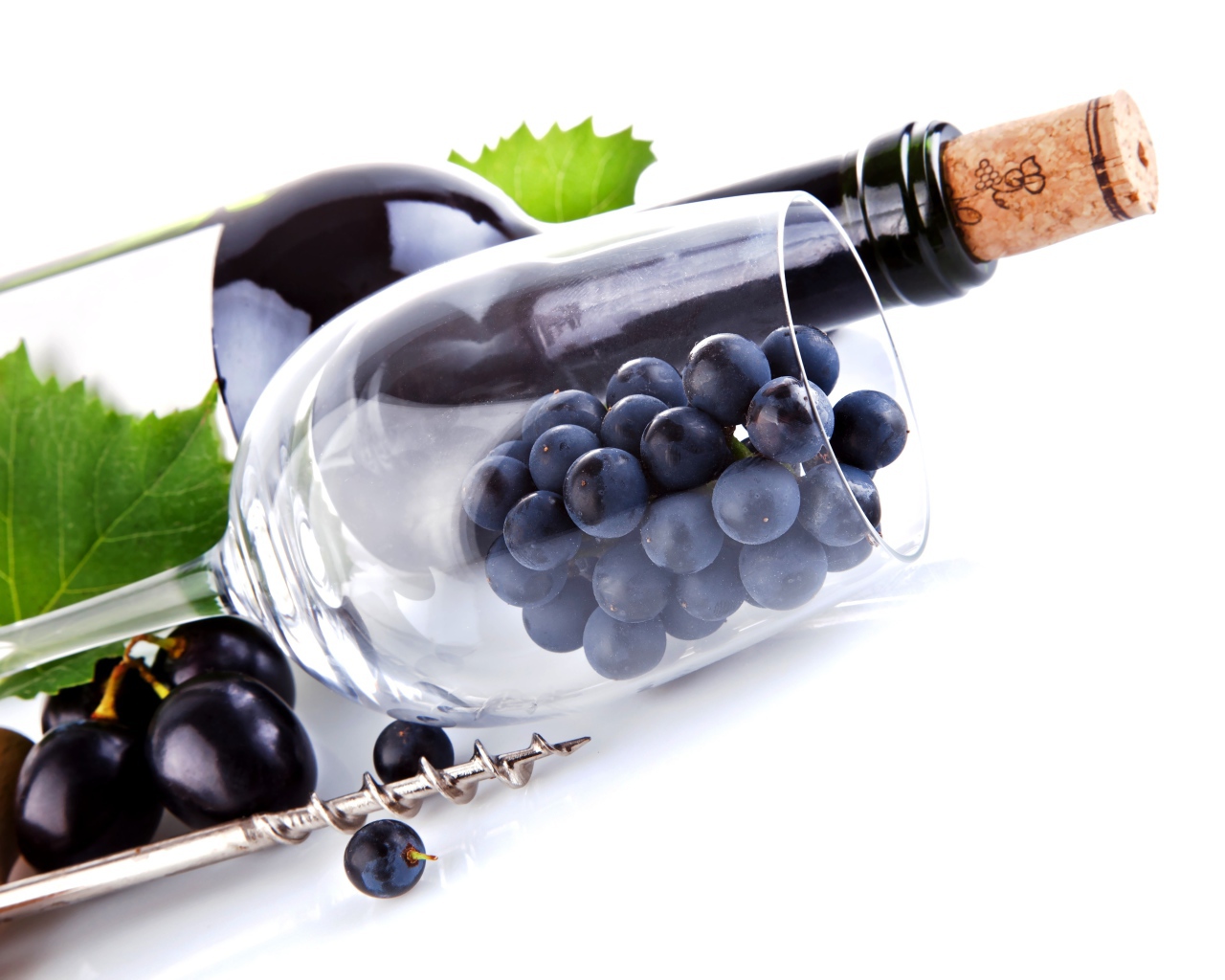 Бутылка вина с бокалом и виноградом на белом фоне