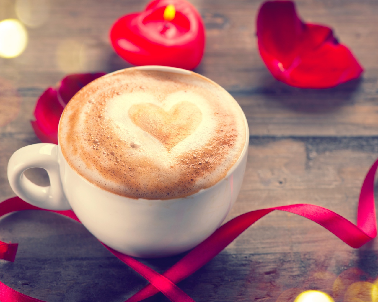Чашка кофе на столе с красной свечой и лентой