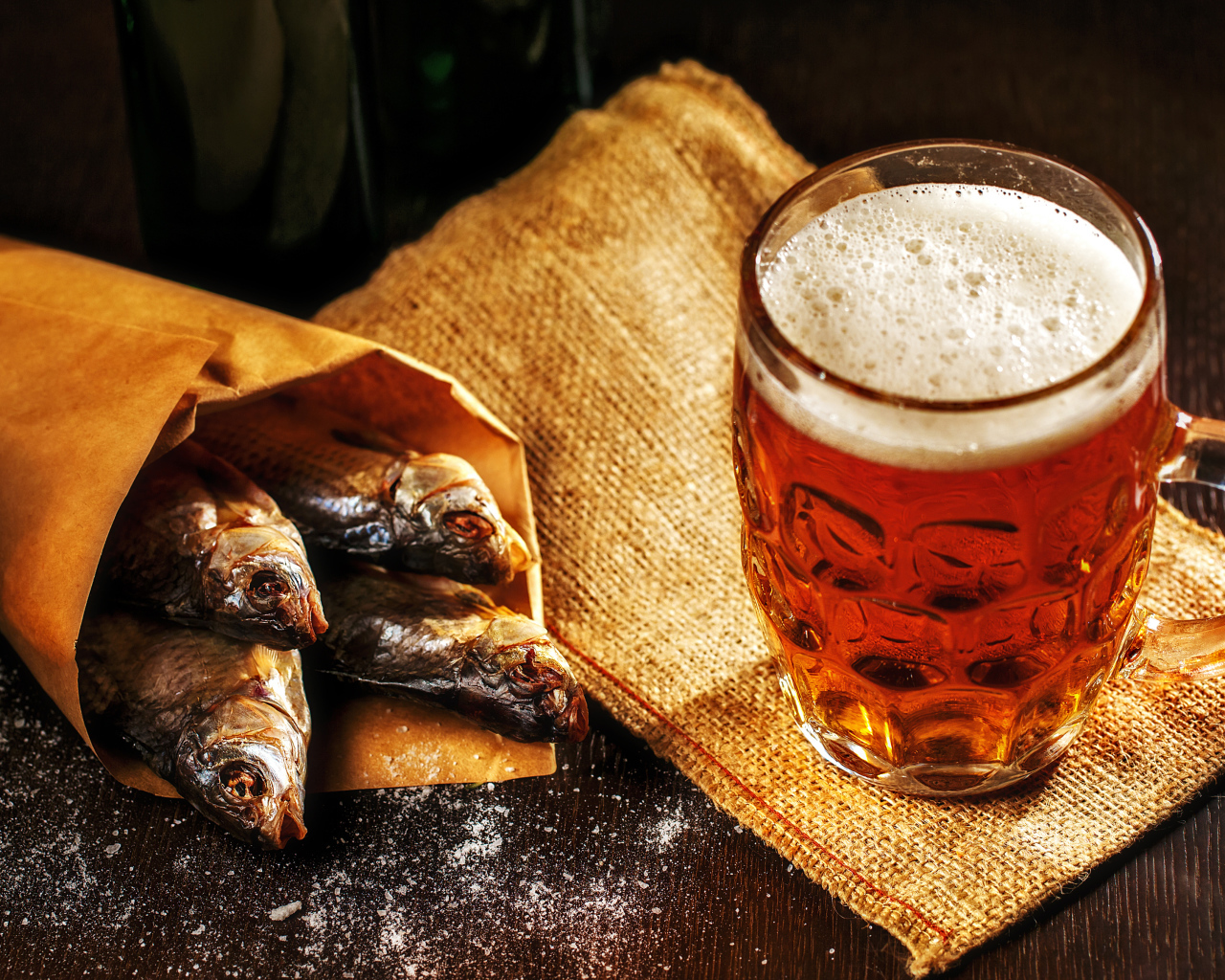 Бокал пива с сушеной рыбой на столе