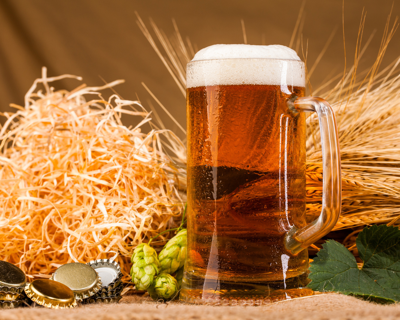 Бокал пива с пеной на столе с хмелем и соломой