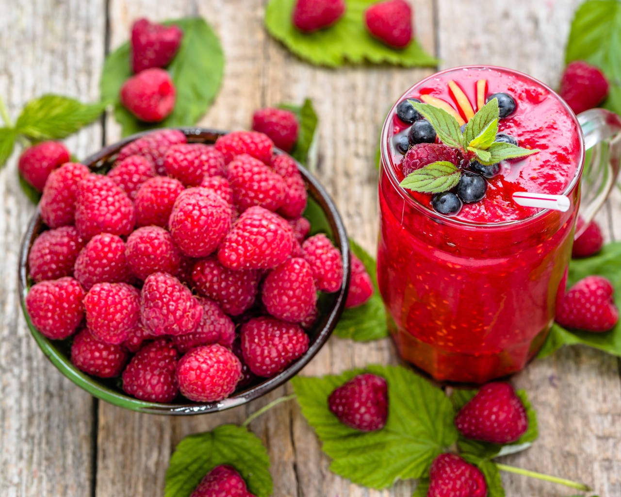 Стакан ягодного смузи на столе со свежими ягодами малины