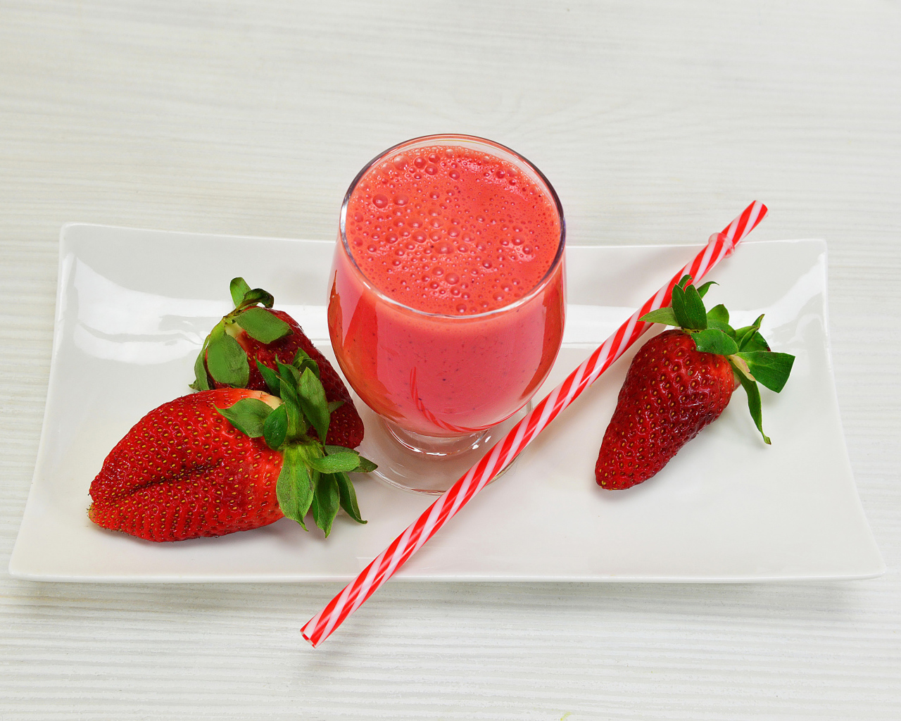 Бокал клубничного коктейля со свежей клубникой и трубочкой