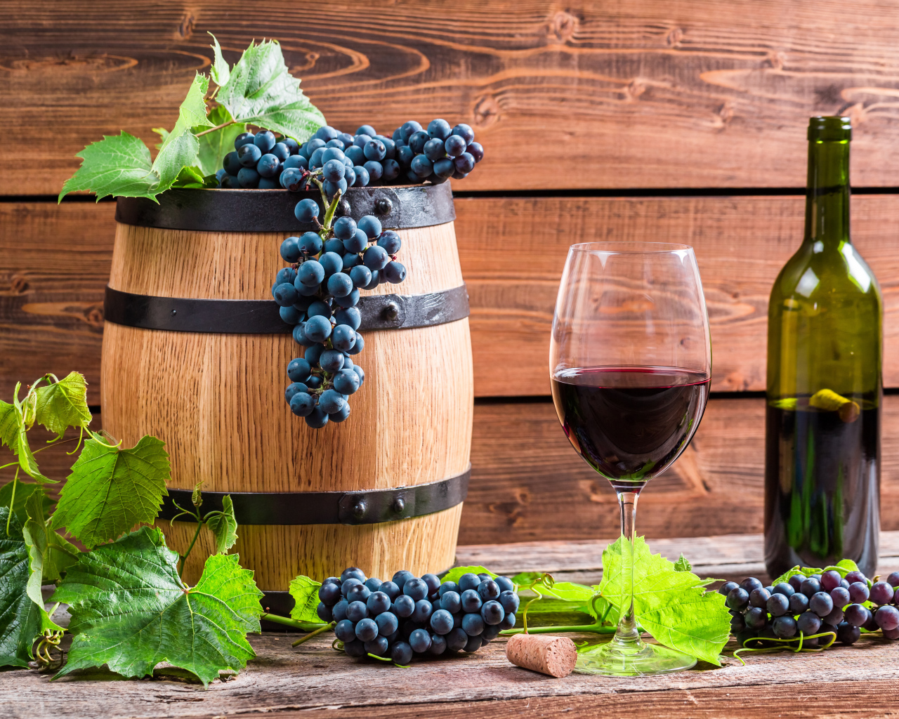 Бокал вина с бочкой и бутылкой на столе с гроздьями синего винограда с листьями