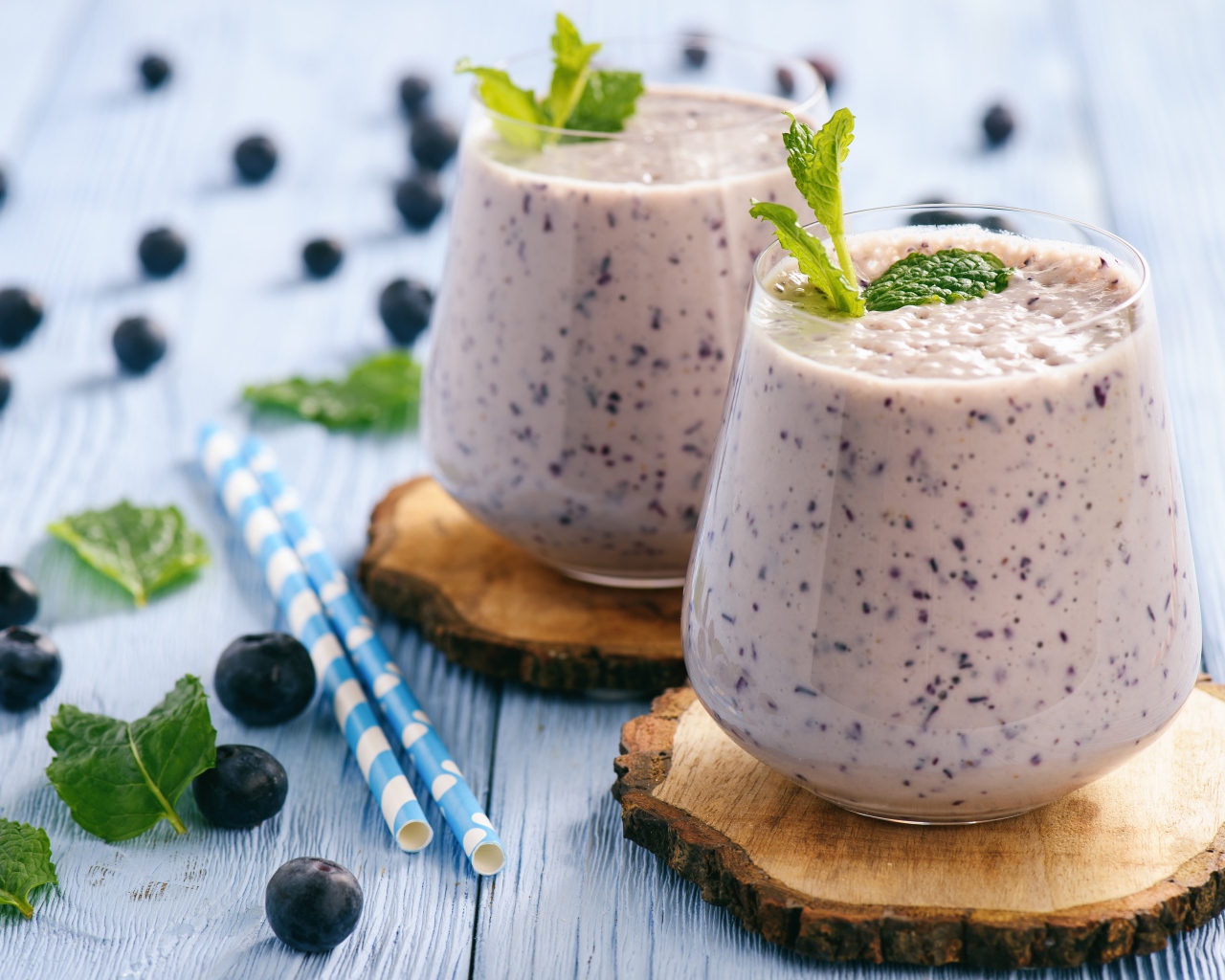 Черничный смузи на столе со свежими ягодами и трубочками