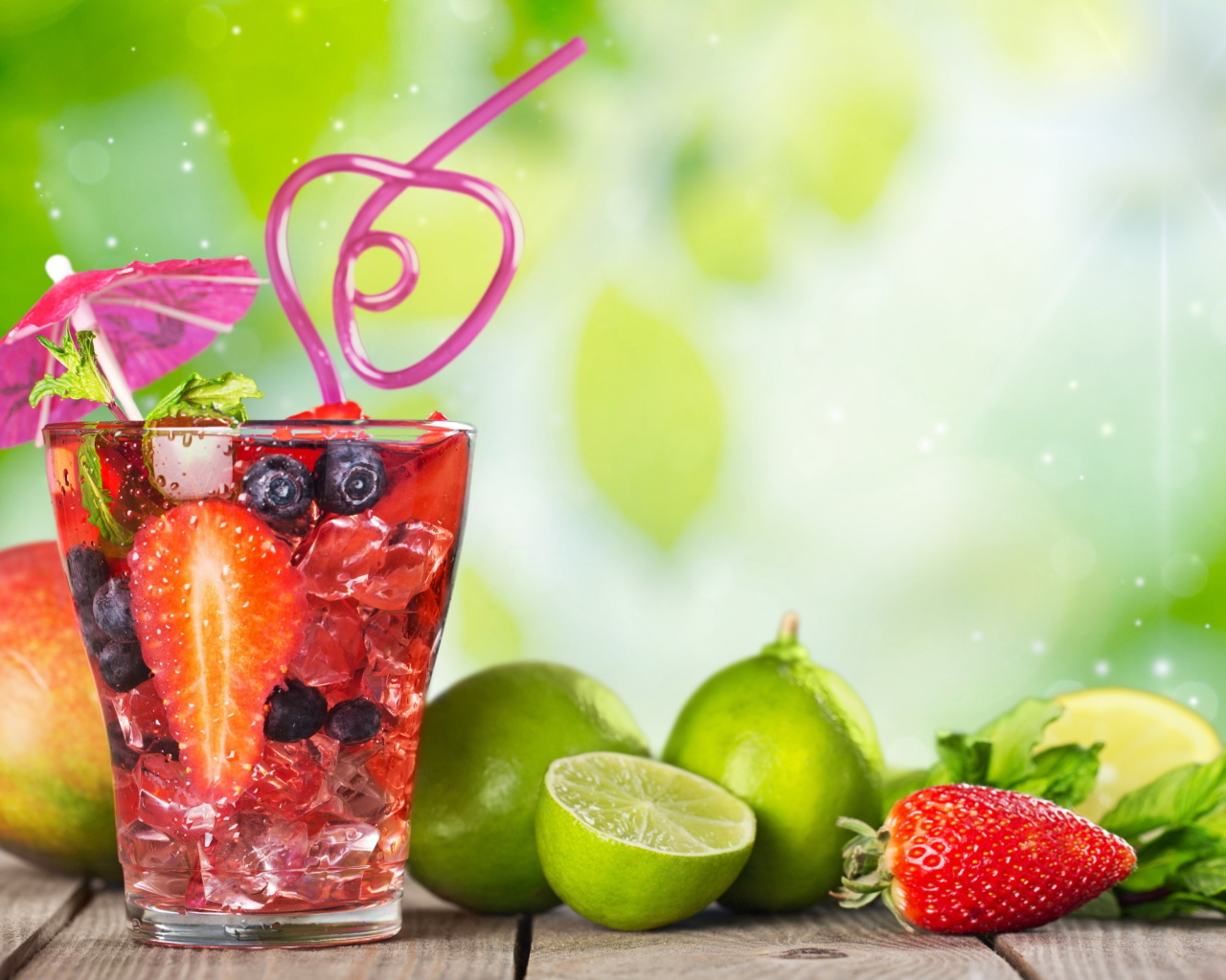 Коктейль с клубникой и ягодами черники в стакане со льдом на столе с лаймами и клубникой