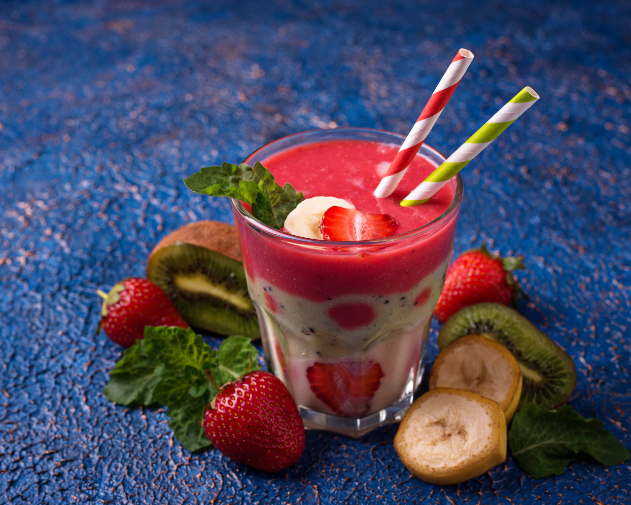 Фруктовый коктейль с клубникой, бананом и киви в стакане с трубочками