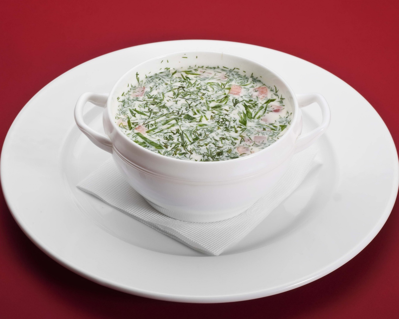 Окрошка в белой пиале на белой тарелке