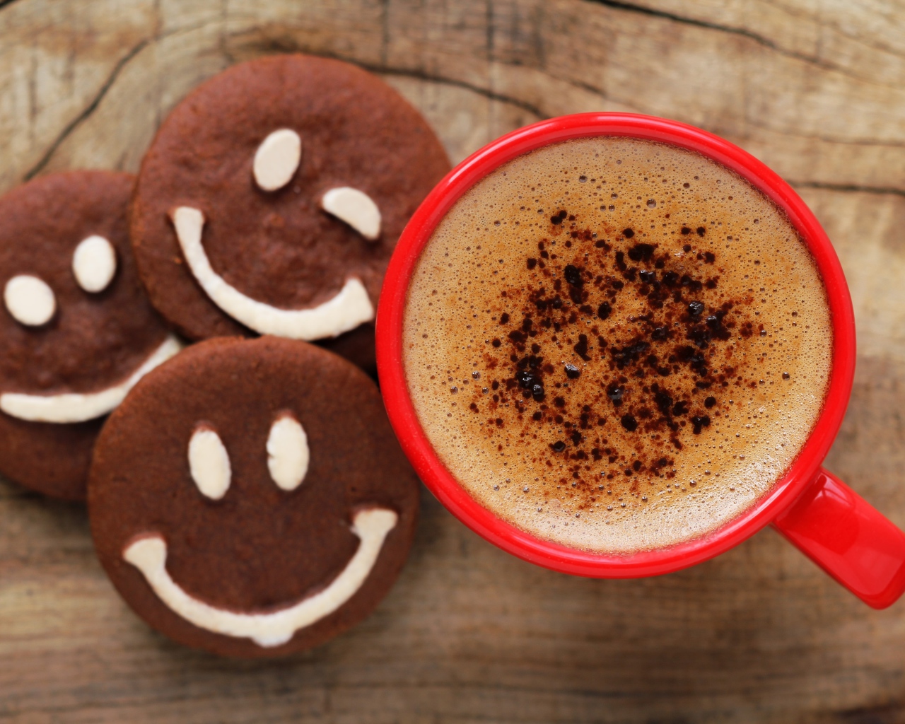 Красная чашка кофе с печеньем смайлами на столе