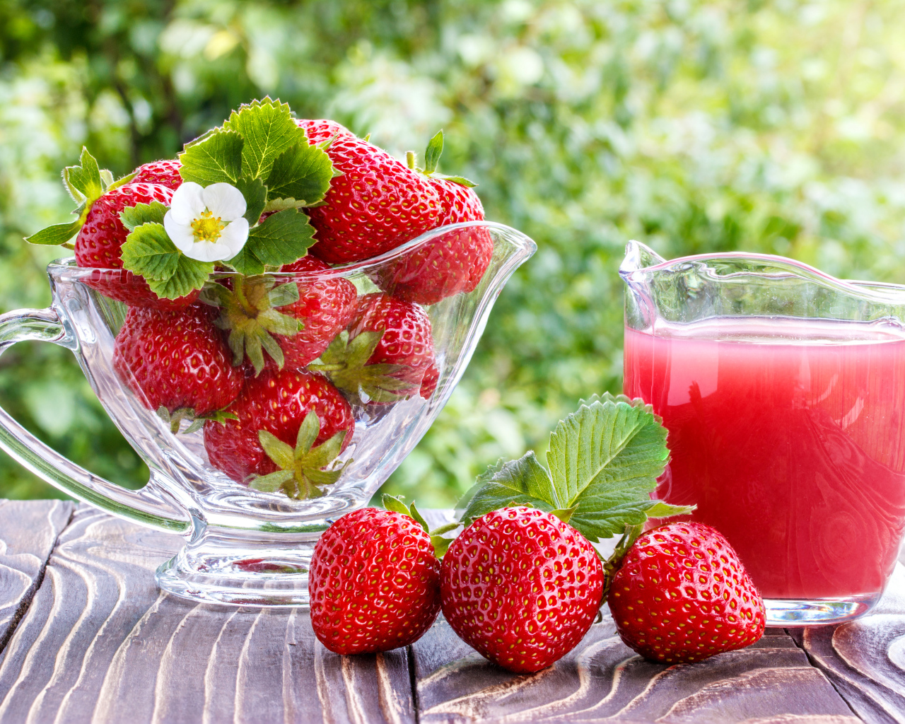 Клубничный сок в стеклянном графине на столе со свежей клубникой