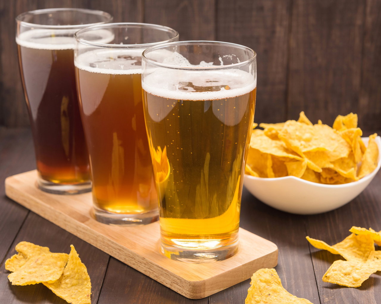 Три стакана пива на столе с чипсами