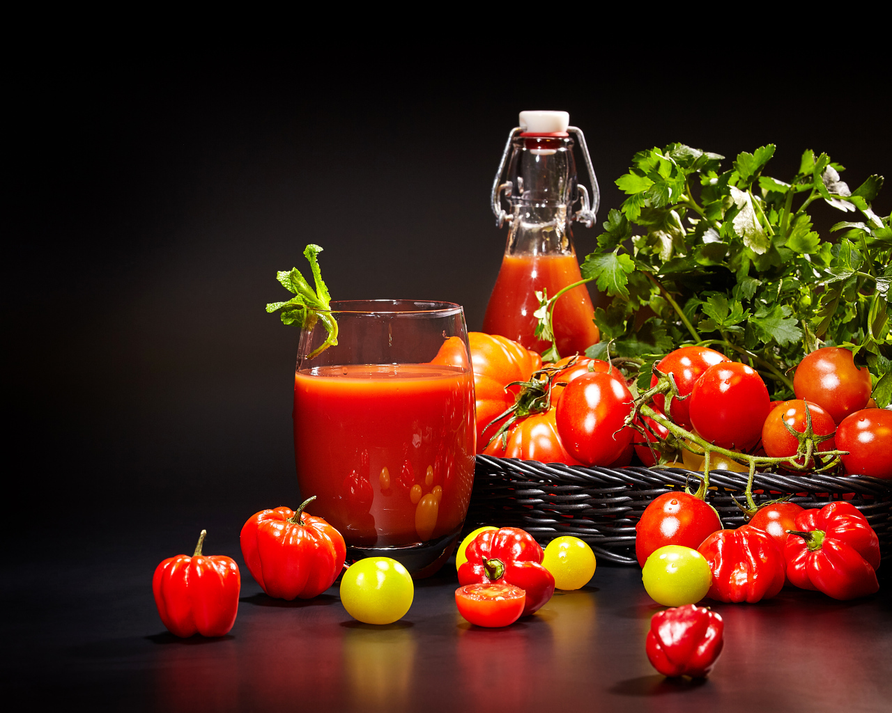 Томатный сок и свежие помидоры на столе на черном фоне