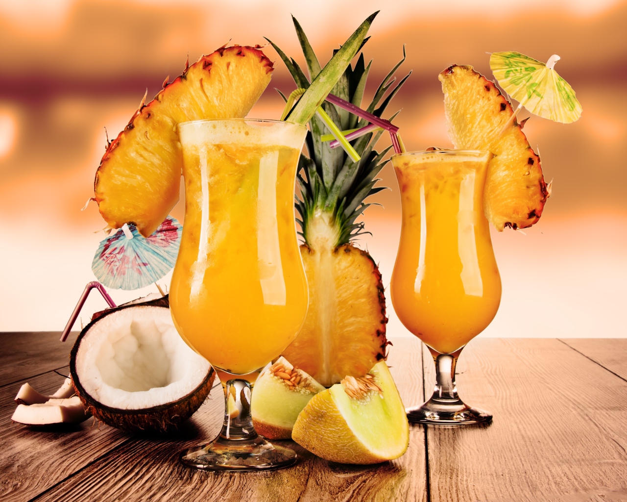 Тропические коктейли на столе со свежими ананасом, кокосом и кусочками дыни