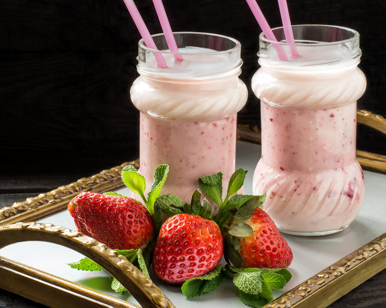 Два свежих клубничных коктейля с трубочками и ягодами клубники