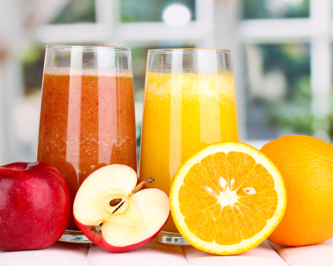 Два стакана с яблочным и апельсиновым соком и свежими фруктами