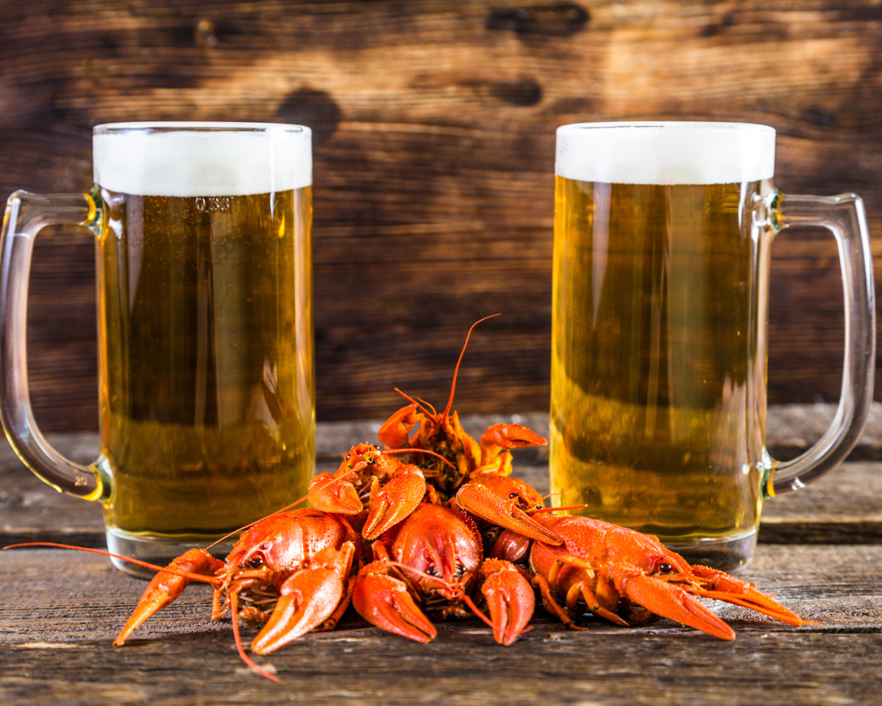 Два бокала пива с красными раками на столе