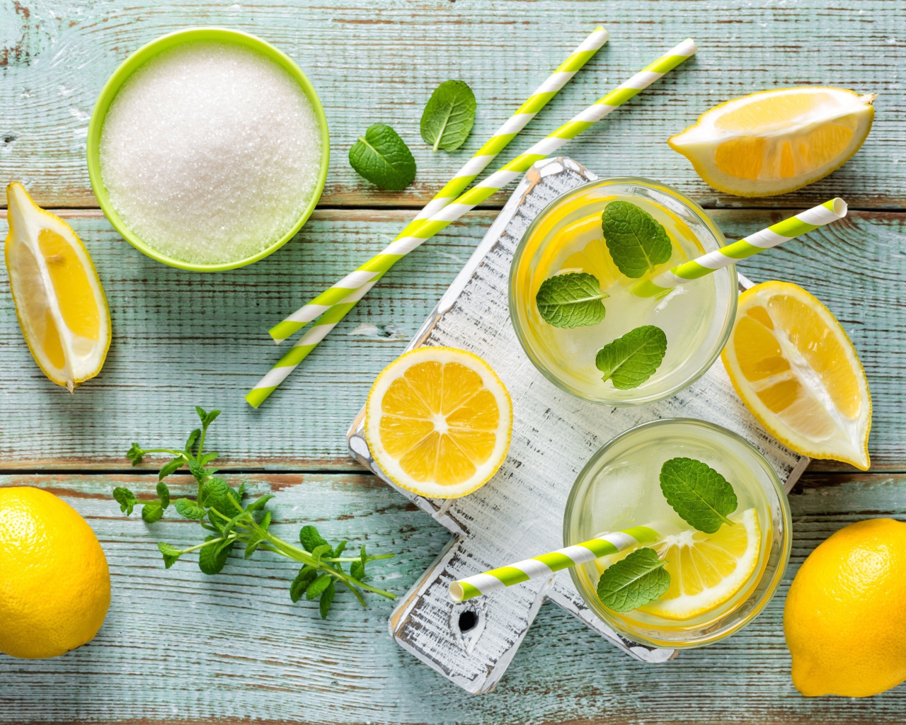Два стакана с лимонадом, мятой, свежими лимонами и сахаром на столе