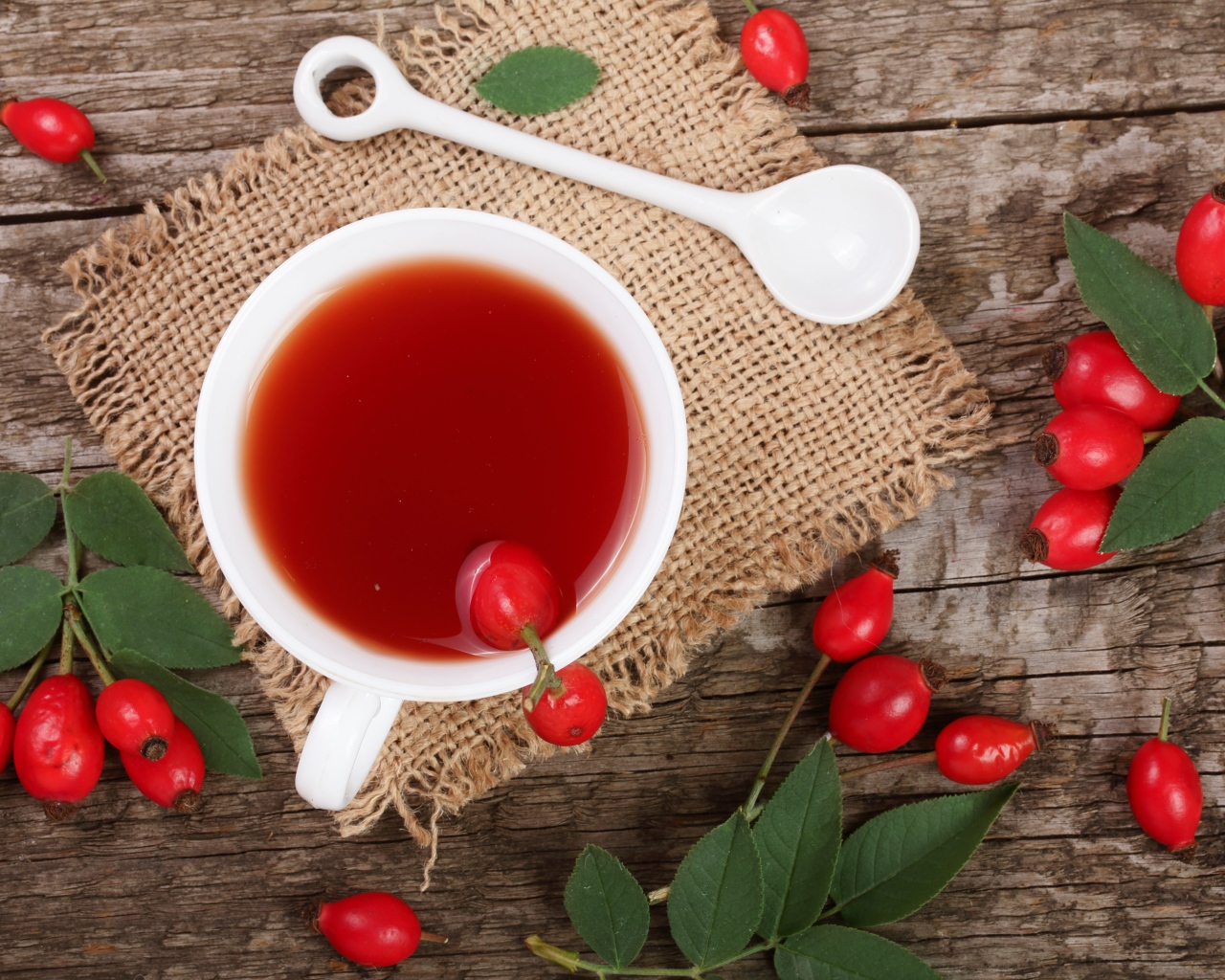 Белая чашка чая с ягодами шиповника на столе