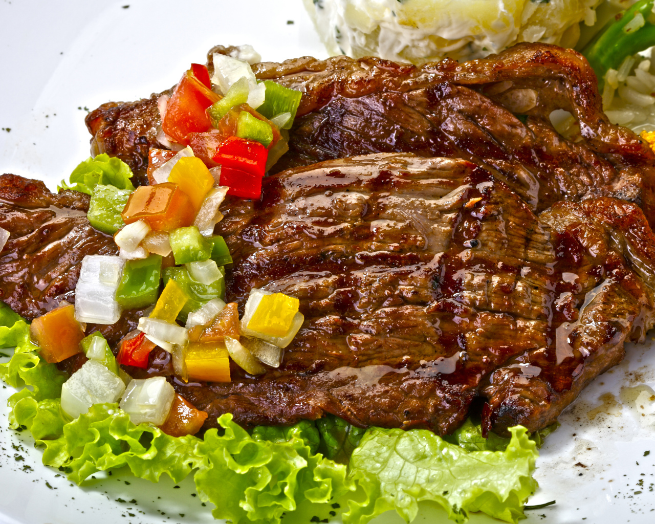 Кусок сочного жареного мяса с овощами и листьями салата