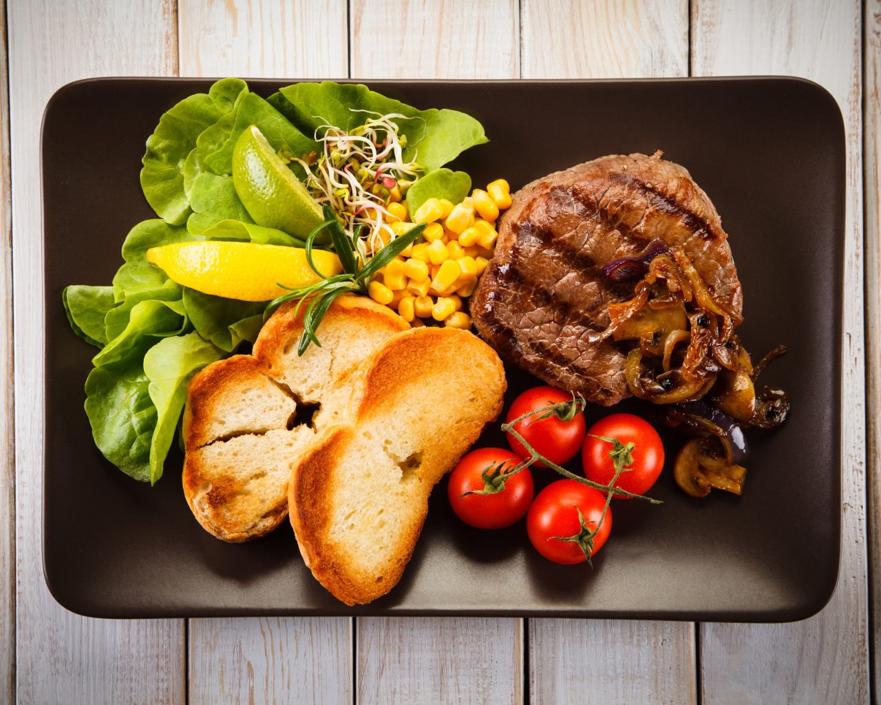 Аппетитный кусок жареного мяса на тарелке с овощами и гренками