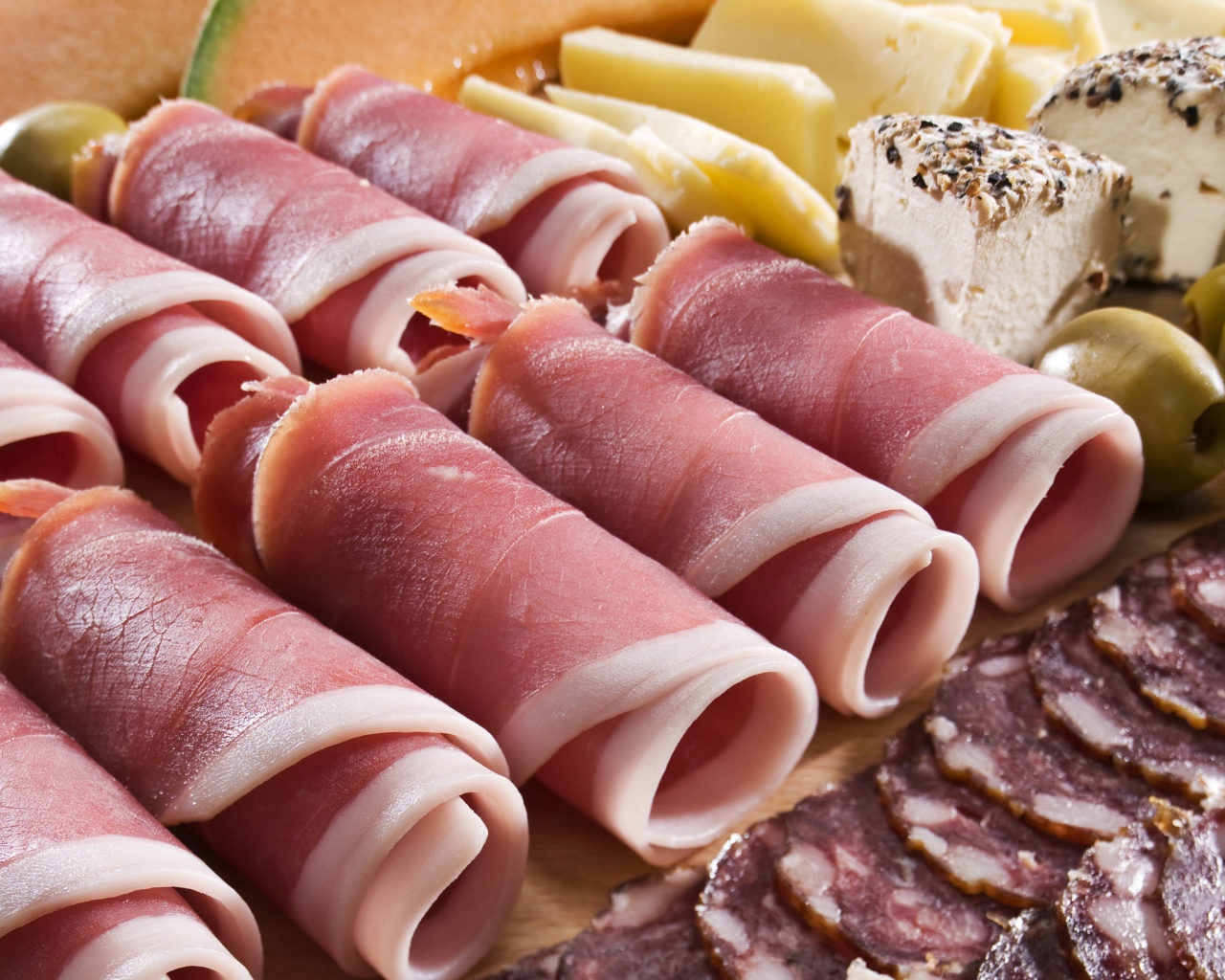 Аппетитные рулетики из бекона на тарелке с зелеными оливками