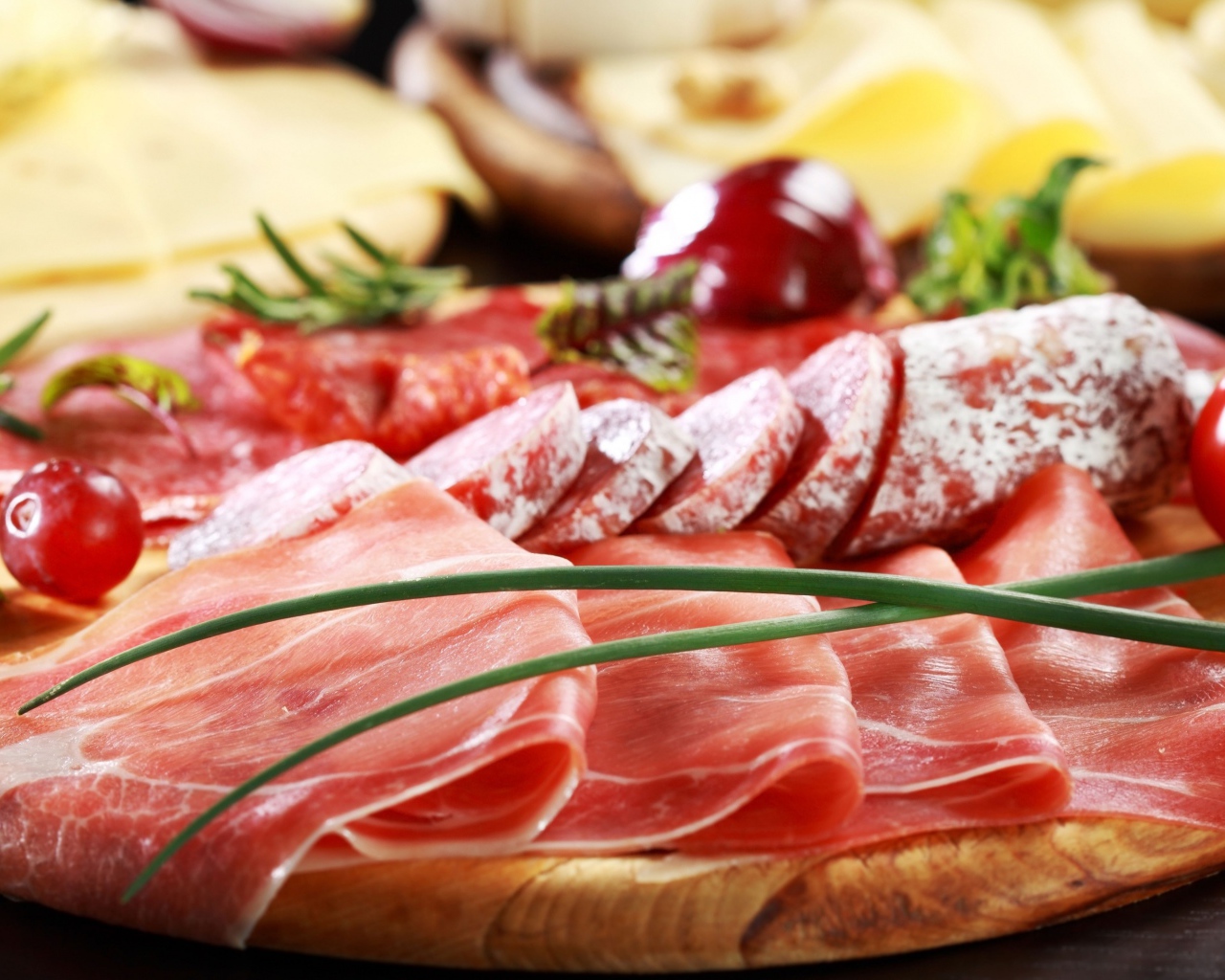 Мясная нарезка на разделочной доске с овощами