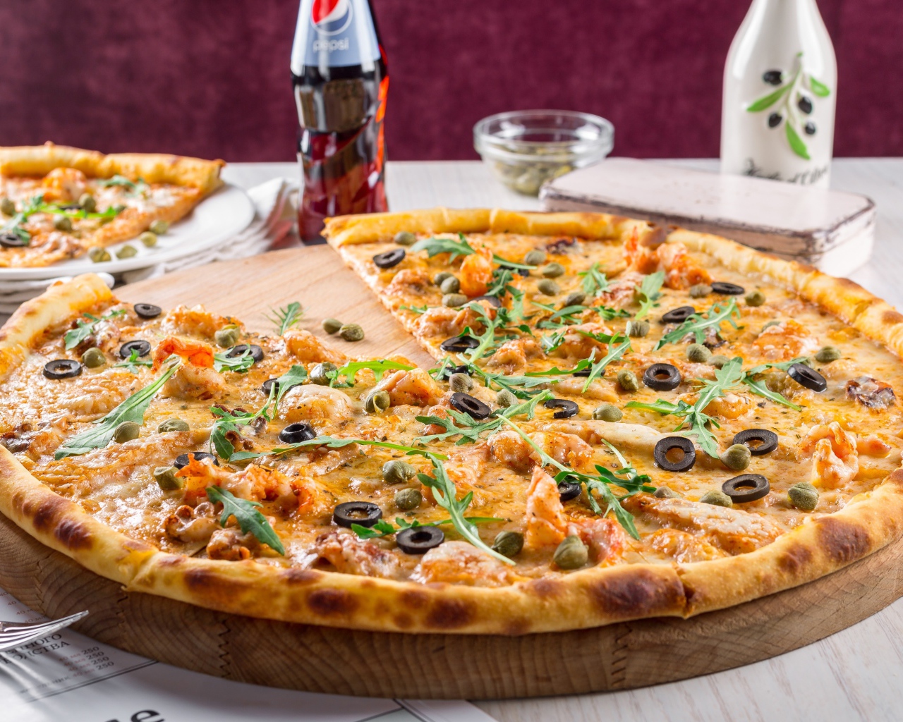 Пицца с оливками на столе с бутылкой пепси