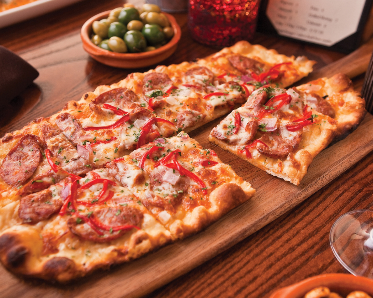 Порезанная на кусочки пицца лежит на разделочной доске