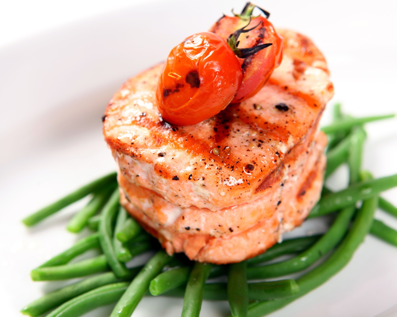 Кусок запеченной рыбы на тарелке с помидорами