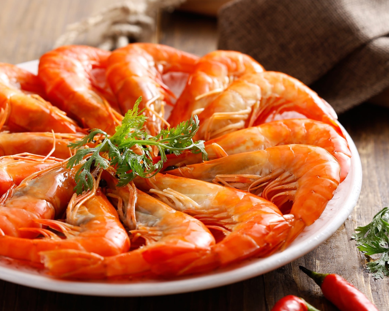 Аппетитные вареные креветки на тарелке с зеленью петрушки