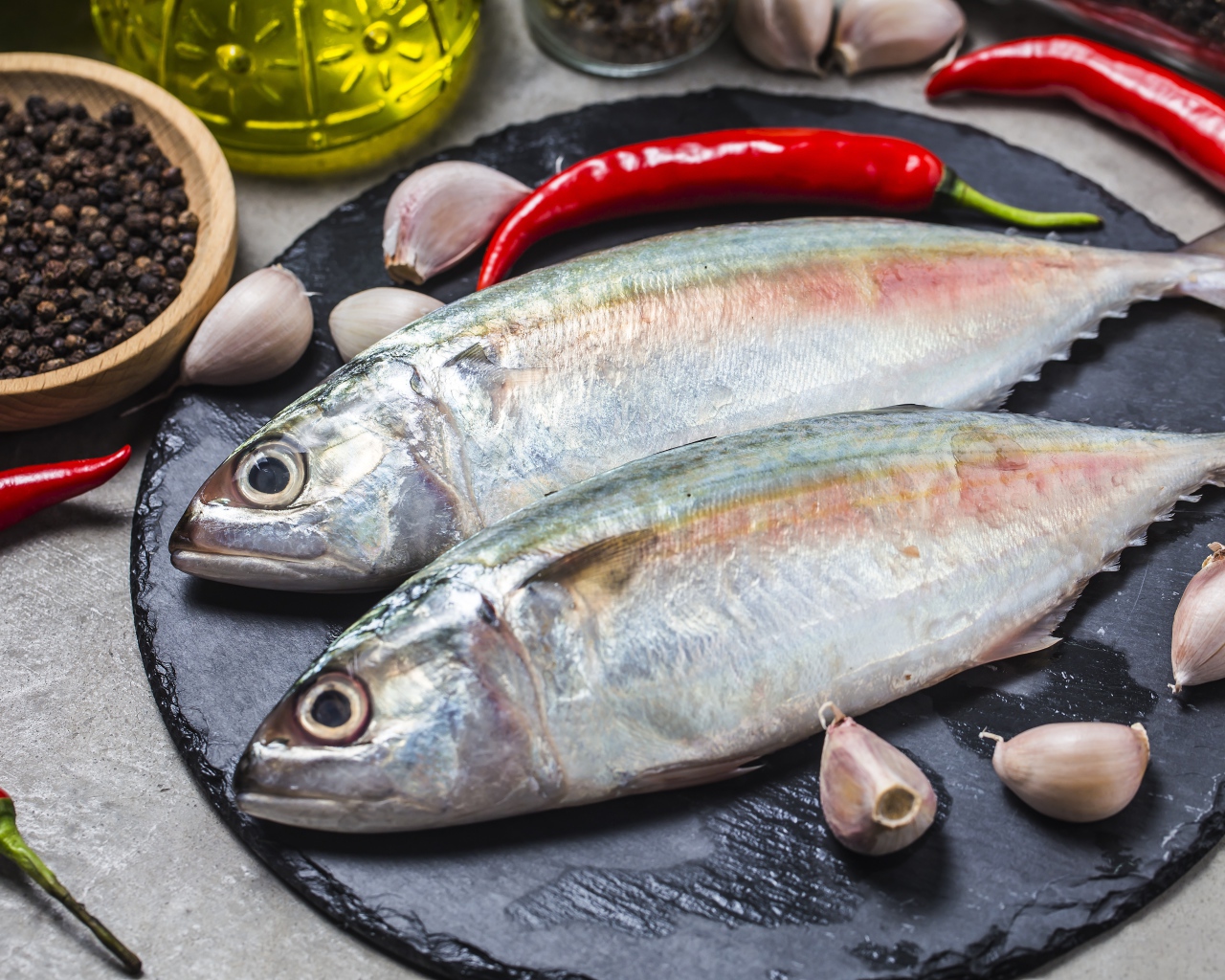 Свежая рыба на столе с красным перцем, чесноком и специями