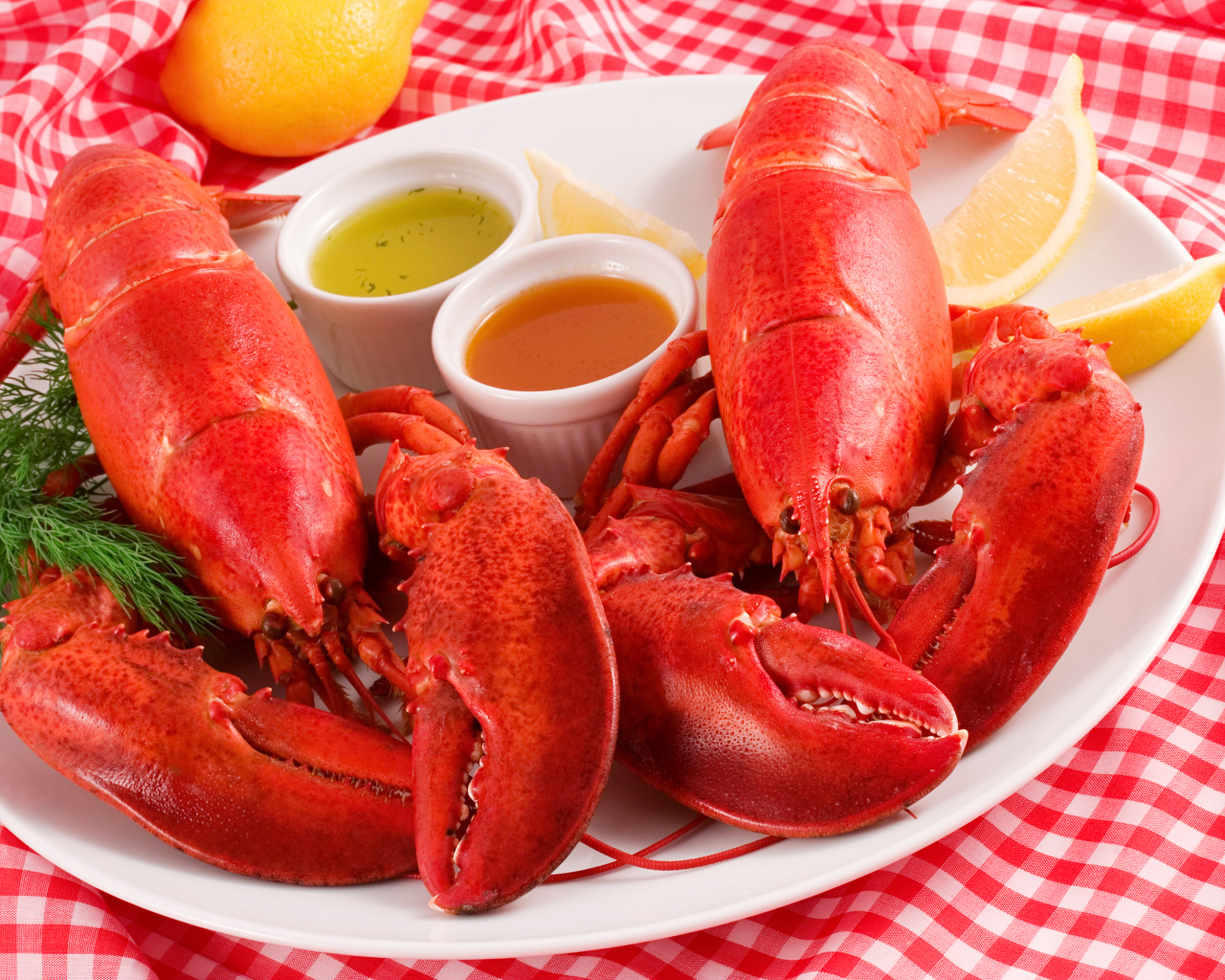 Два вареных омара на тарелке с соусом