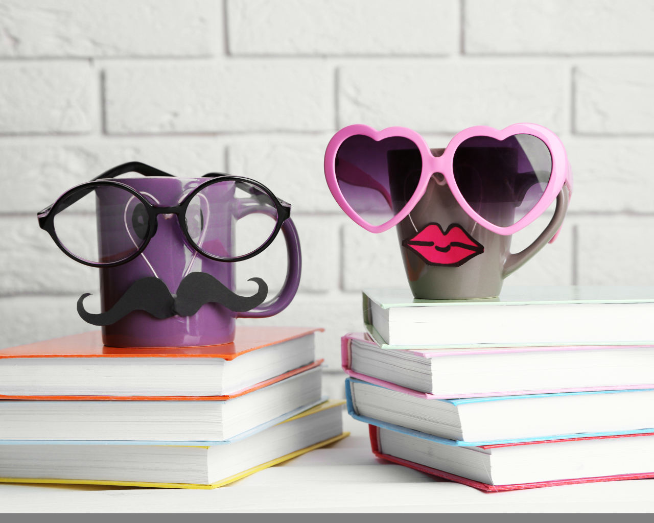 Two funny cups in glasses stand on books