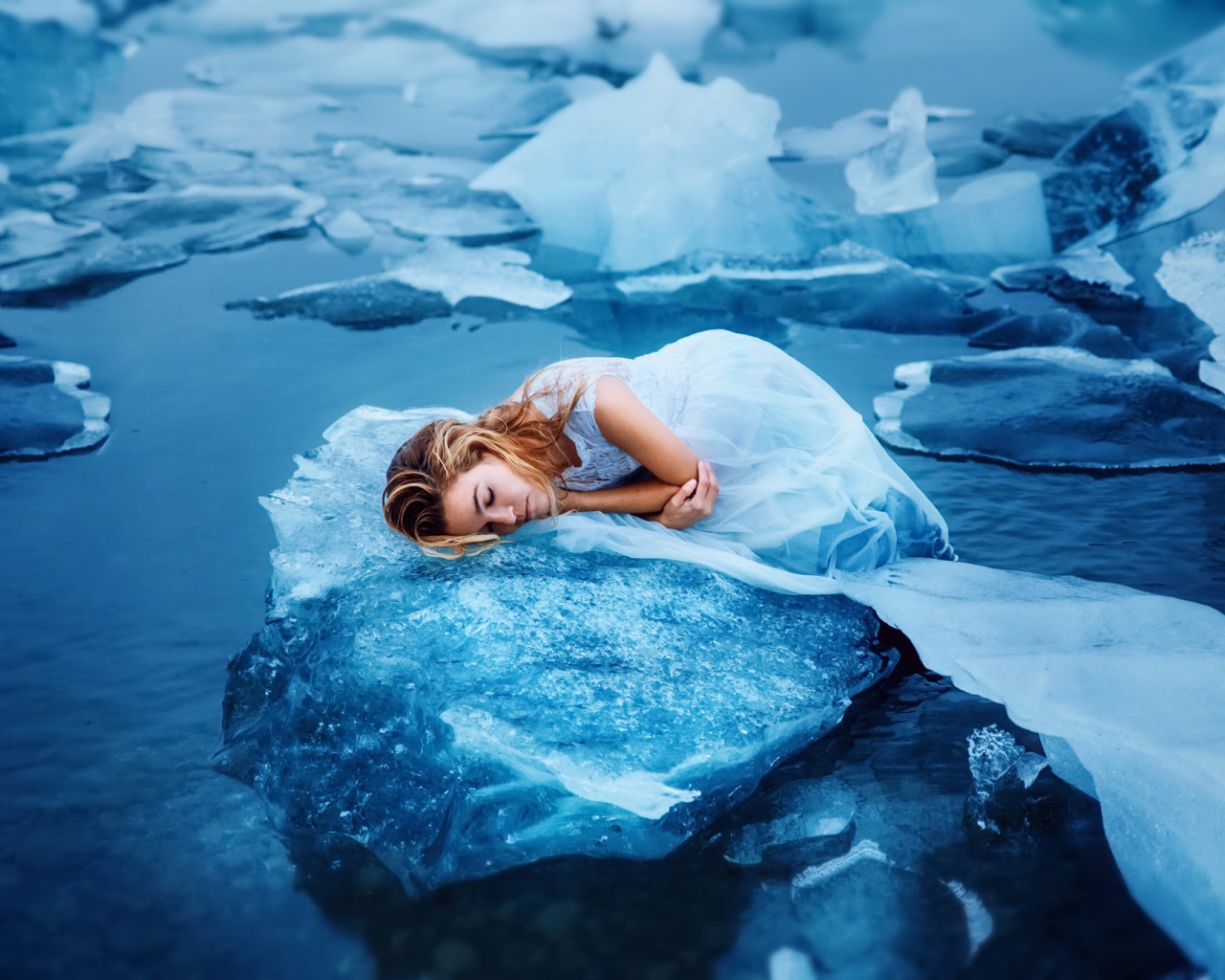 Девушка в красивом белом платье лежит на льдине