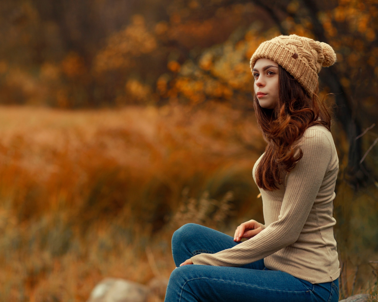 Молодая девушка в синих джинсах и теплой шапке