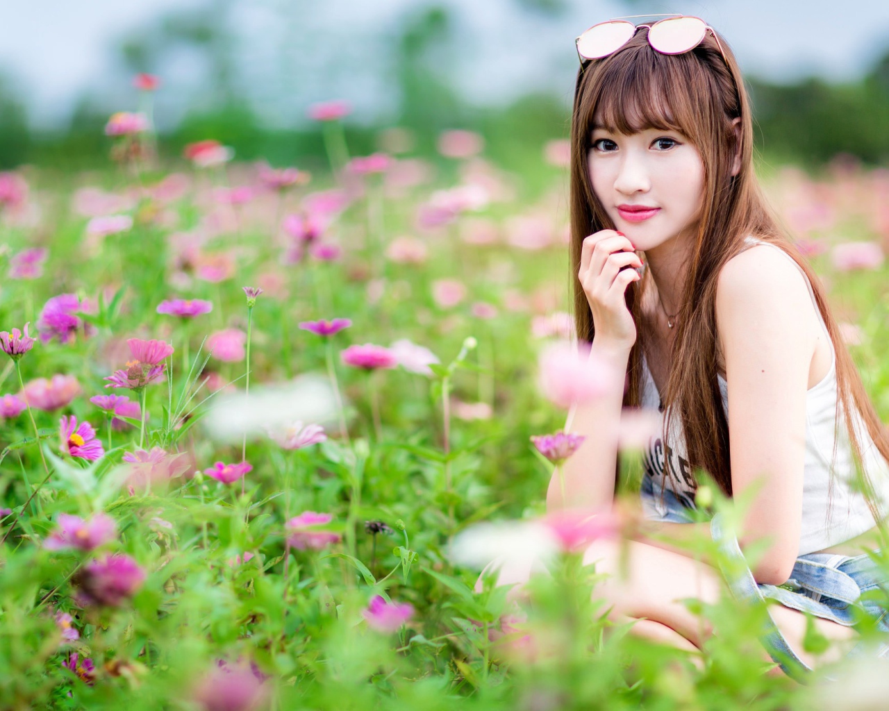 Красивая девушка модель азиатка на поле с розовыми цветами