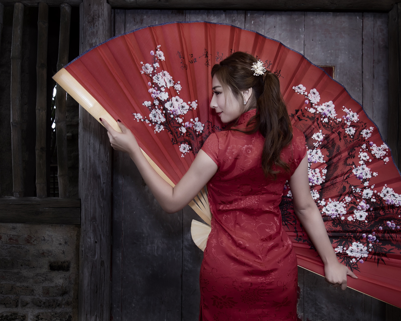 Красивая девушка азиатка в красном платье с большим веером
