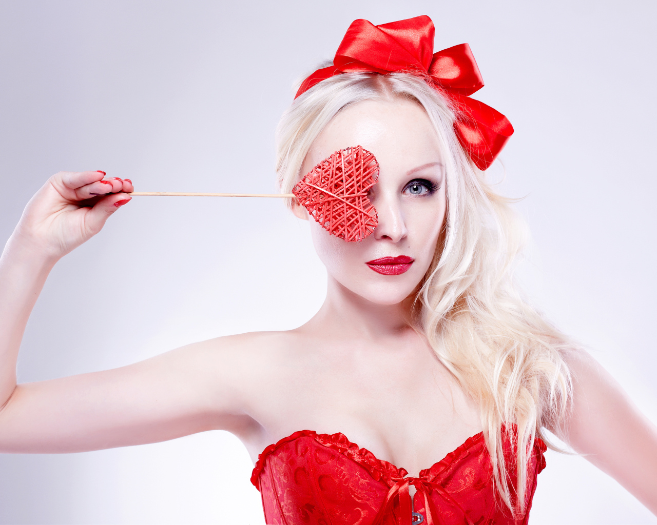 Красивая девушка блондинка в красном наряде с сердечком в руке