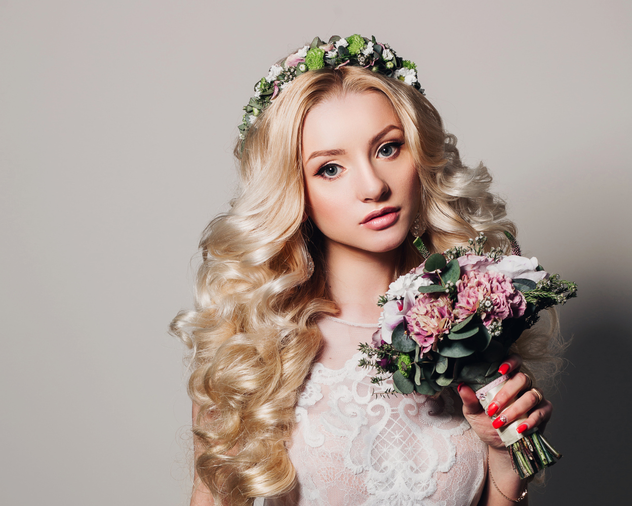 Красивая блондинка в свадебном платье с букетом цветов на сером фоне
