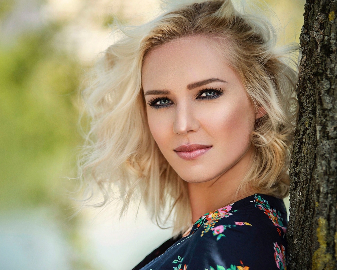 Красивая блондинка с голубыми глазами у дерева 