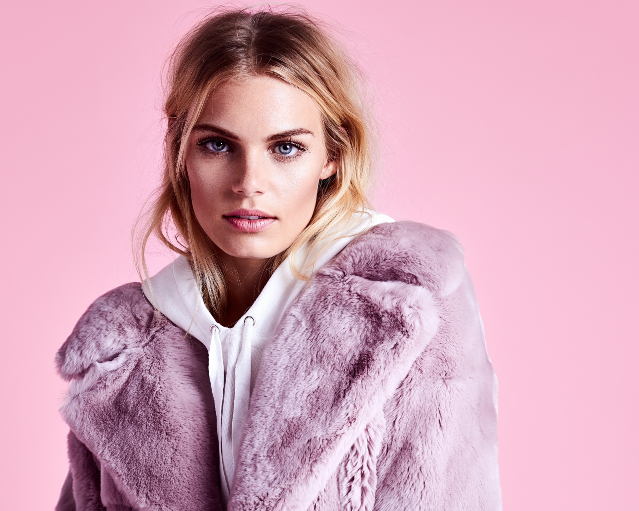 Красивая голубоглазая девушка в шубе на розовом фоне