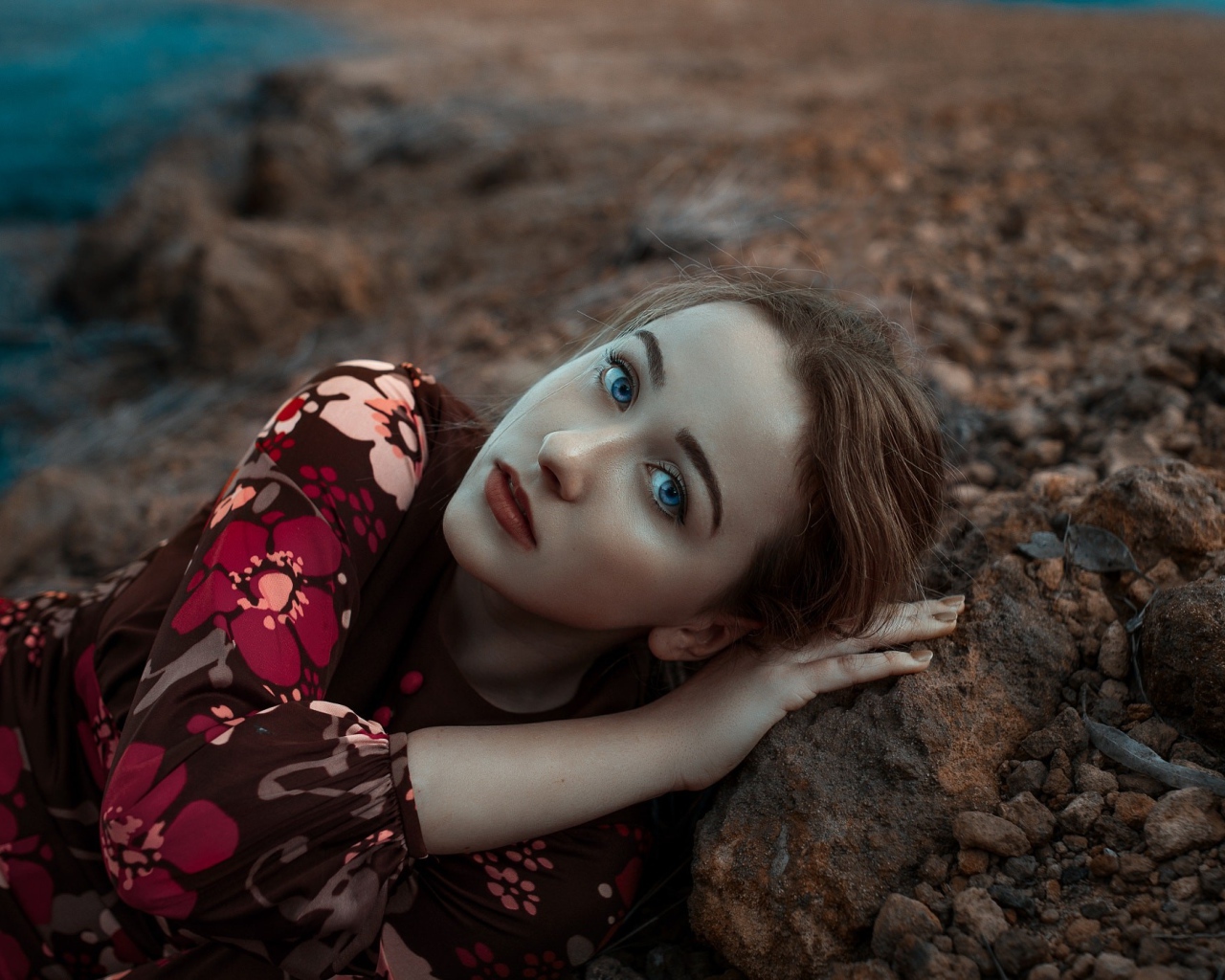 Красивая голубоглазая девушка лежит на камне 