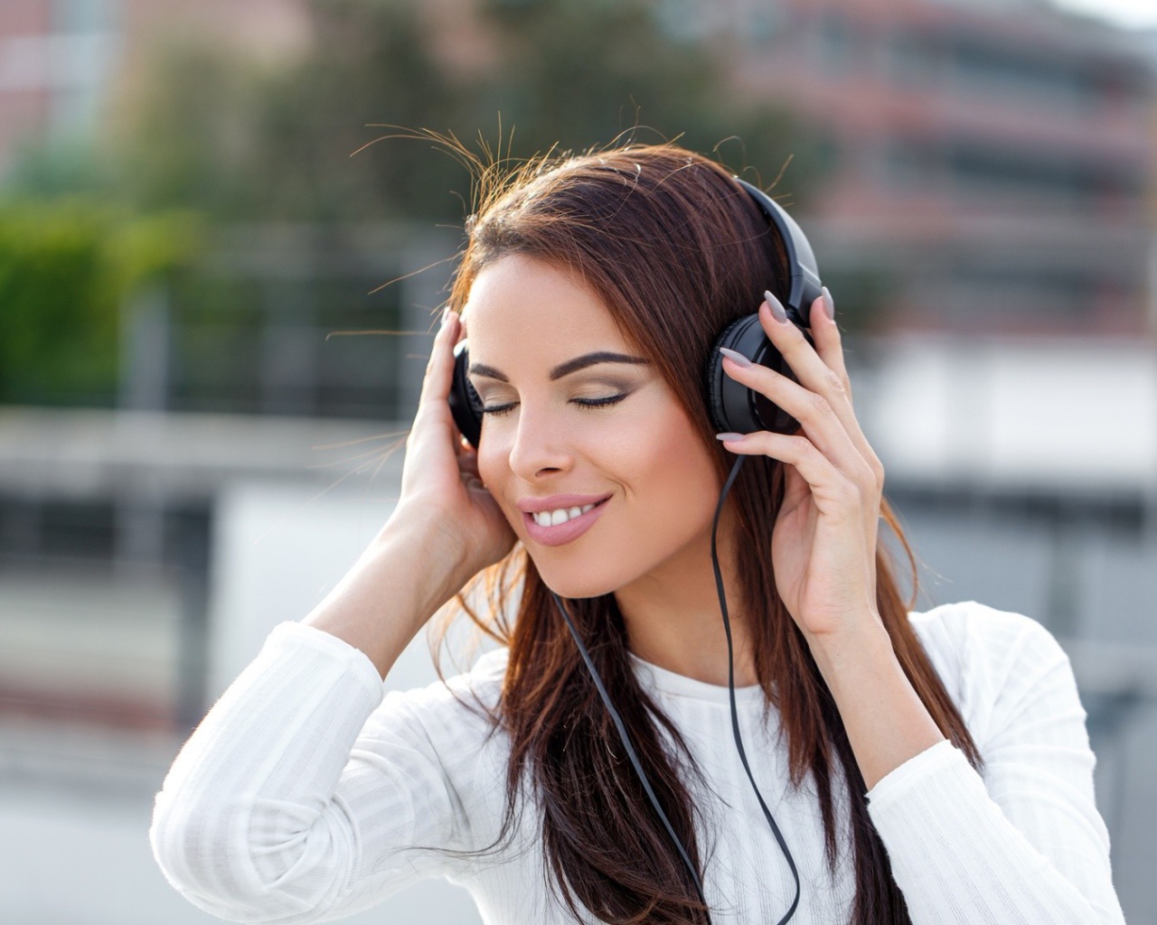 Красивая девушка брюнетка слушает музыку в наушниках 