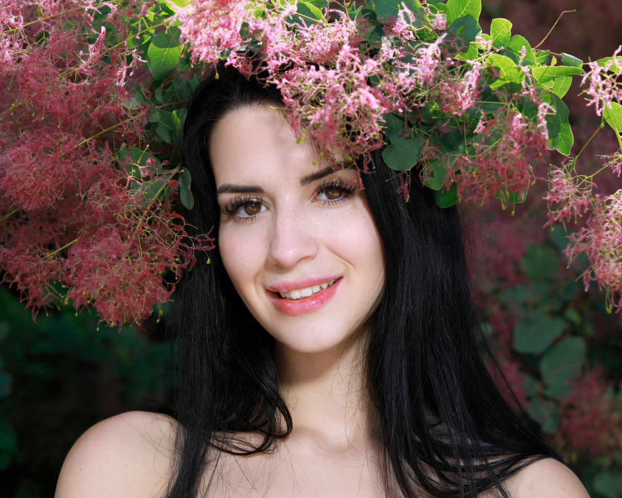 Красивая брюнетка стоит у цветущей ветки